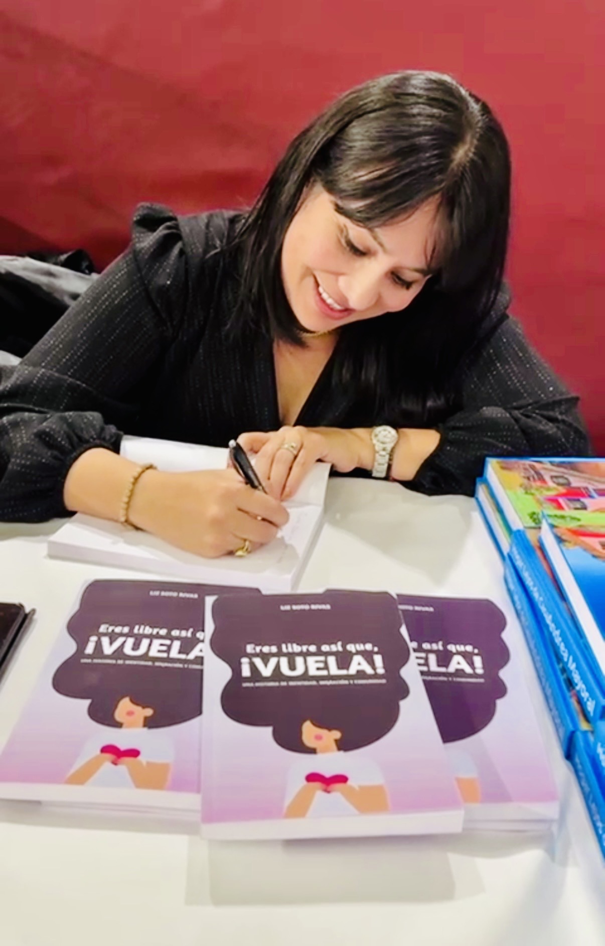 Liz Soto Rivas firmando ejemplares de Eres libre, ¡así que vuela!