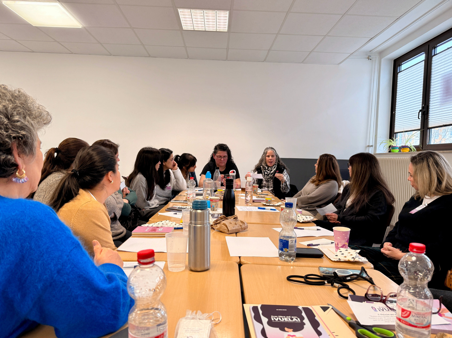 Taller alrededor de una mesa larga con mujeres conversando y ejemplares del libro